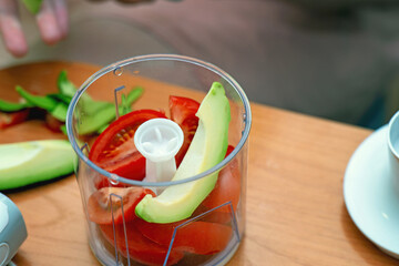 Sliced tomatoes and avocado in a blender container, ready to be processed into fresh homemade guacamole