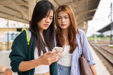two young women talking on the phone in train station
