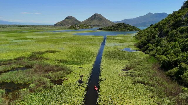Aerial view of Rijeka Crnojevica between mountains flowing into Skadar Lake, Montenegro. People kayaking on beautiful river. 