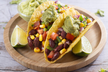 Vegan mexican tacos with beans and avocado on wooden table