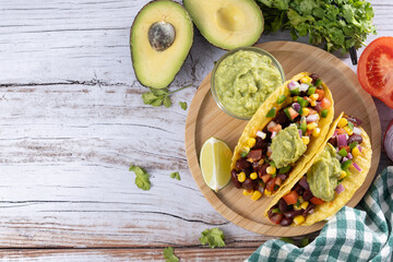Vegan mexican tacos with beans and avocado on wooden table. Top view. Copy space