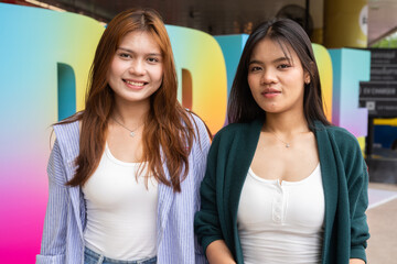 Fototapeta premium Young lesbian LGTB couple posing in front of pride text outdoors in city