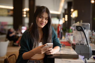 young woman texting on mobile phone in cafe