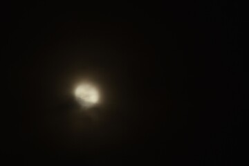 blurry full moon covering by cloud floating on sky in night background