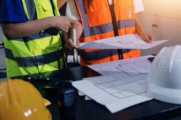Closeup of team of industrial engineers meeting analyze machinery blueprints consult project on...