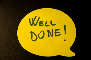 Photograph of a yellow emoji on a black background with congratulations "well done" hand written .