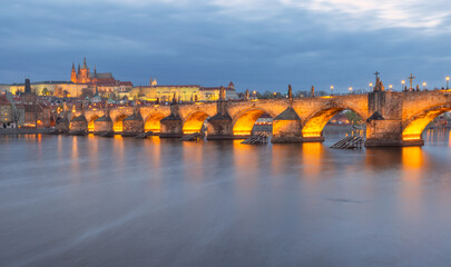 Illuminated Charles Bridge in Prague Czech Republic seen at dusk over the Vltava River