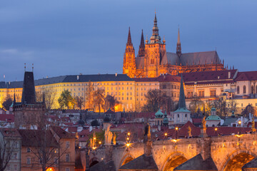 St Vitus Cathedral in Prague Czech Republic illuminated at dusk with city buildings in foreground