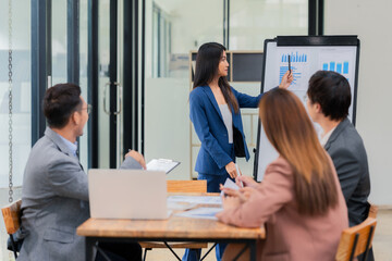 Group of Asian business people discussing charts and graphs showing the results of successful business investment and growth showing the results of successful teamwork.