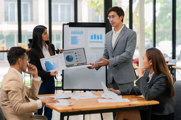Group of Asian business people discussing charts and graphs showing the results of successful...