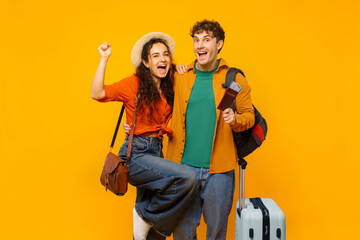 Excited European couple with suitcase and tickets making victory gesture, ready for vacation,...