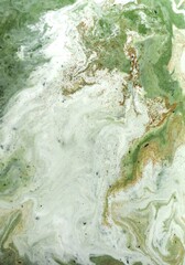 Abstract art featuring a swirling mix of green white and gold colors paint