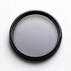 A close-up photo of a circular, black camera lens filter on a white textured surface, showcasing reflective glass and a sleek frame.