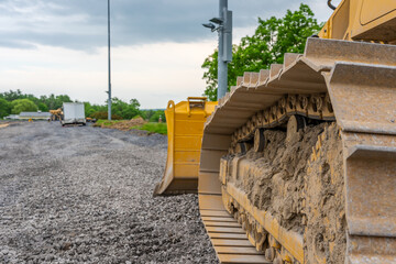 Closeup photo of dirty, dried mud, on a bulldozers, crawler, metal tracks on construction Site.
