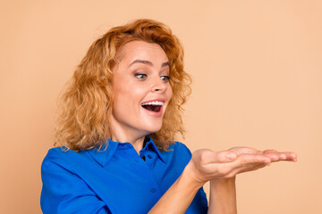 Enthusiastic woman with red hair wearing a blue shirt cheerfully gesturing with her hands against a...