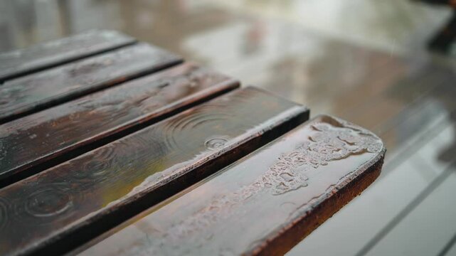 Wet wooden table, reflecting splashing raindrops and creating intricate patterns on its surface