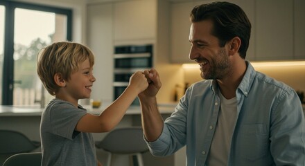 A father and son share a joyful fist bump, celebrating a moment of connection and happiness in a bright, modern kitchen setting.