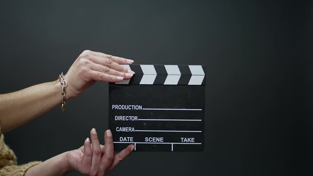 Person's hands holding a clapperboard with a dark background, symbolizing film production