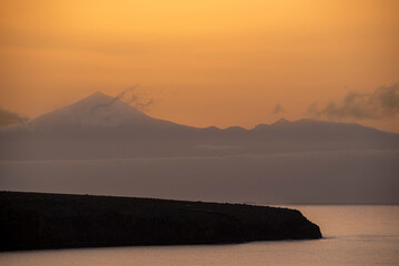 A mountain range is visible in the distance, with a body of water in the foreground. The sky is a mix of pink and gray, creating a serene and peaceful atmosphere