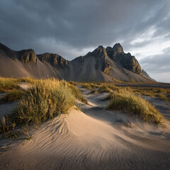 View of vestrahorn mountain from a sandy beach with tall grass under a cloudy sky in iceland