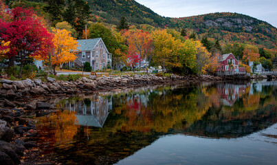 Autumn landscape reflecting on the water with houses and colorful trees in a coastal setting view