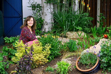 Woman in a garden rockery, in summer.