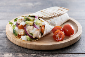 A delicious grilled chicken wrap with vegetables on wooden table