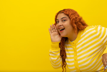 Red haired freckled woman wearing a yellow with white striped shirt, peeking out and happily waving...