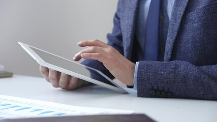 Businessman is using a digital tablet to analyze financial data, working with modern technology in the office to improve productivity and decision making. Business people concept - Powered by Adobe