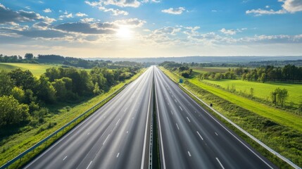 Naklejka premium A modern motorway stretching into the horizon, surrounded by lush green landscapes and a bright blue sky.