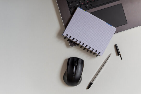Top view of home office workspace with supplies like wireless mouse, laptop, pen and laptop.