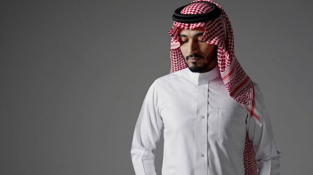 Handsome arab middle-eastern saudi arabian man with traditional saudi clothing in studio - Arabic muslim adult male businessman wearing thwab portrait isolated on gray background