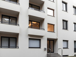 Modern apartment facade with clean lines, bathed in natural light, set in a minimalist urban environment. Simplicity and elegance in contemporary a