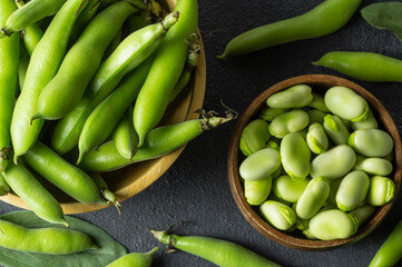 Fresh broad beans with pod in bowl on dark rustic background, healthy food