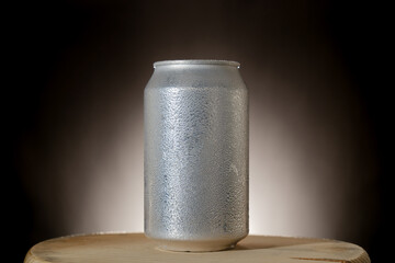 Silver beer can with copy space on rustic wooden table and dark smoky background.