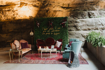 Eclectic vintage wedding lounge setup with velvet furniture, greenery backdrop, floral accents, and...