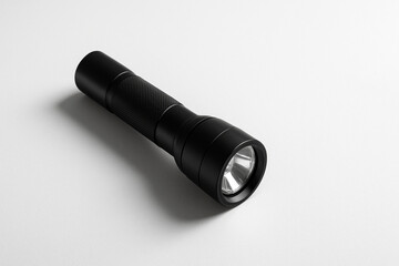 白い背景に置かれたシンプルな黒い懐中電灯