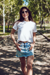 Happy Young Woman In White T-Shirt And Denim Skirt Walking In Park