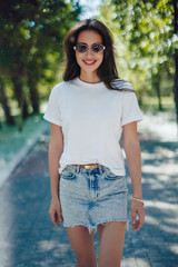 Happy Young Woman In White T-Shirt And Denim Skirt Walking In Park