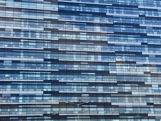 A Modern Glass Building featuring a Reflective Facade, Standing Tall Against a Bright Blue Sky....