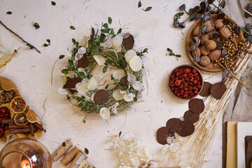 Flat lay of a completed handmade dried flower wreath placed on a bright wooden table, surrounded by...
