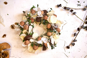 Flat lay of a completed handmade dried flower wreath placed on a bright wooden table, surrounded by...