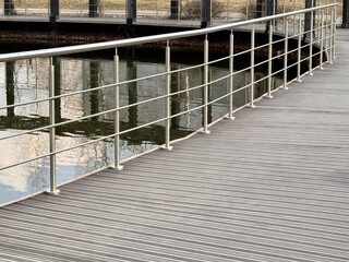 A Stylish Walkway Featuring Elegant Railings Alongside a Peaceful and Tranquil Water Body. A modern walkway designed with stainless steel railings gracefully lines a calm and serene body of water