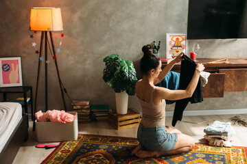 Young woman folding clothes after party at home
