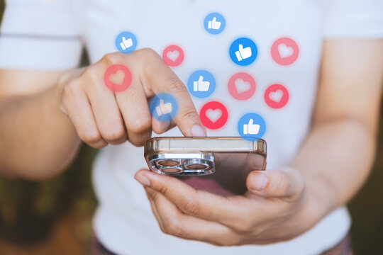 Woman checks smart phone mobile for likes and hearts in social media. Social network sharing and commenting in the online community, Holding phone and using application social media with icon heart - Powered by Adobe