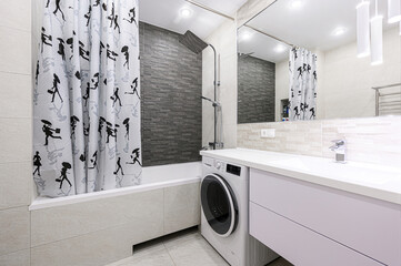 Modern bathroom featuring a shower with a unique curtain, a washing machine, a large mirror, and...