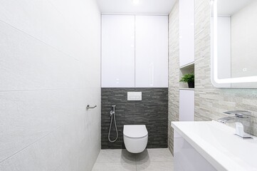 modern, minimalist bathroom with gray and white tones, featuring a floating toilet, sleek sink, and...