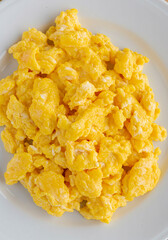 Overhead view of scrambled eggs on a white plate