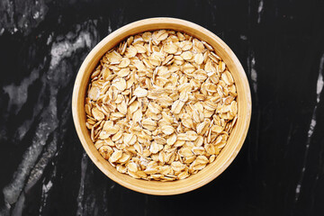Raw oats in bamboo bowl. Healthy organic grain for breakfast. Top view on marble table. Rustic natural background. Vegan dietary fiber source. Clean eating concept. Natural whole grain.