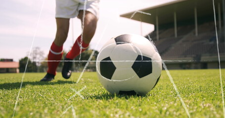Player wearing white shorts, red socks kicking soccer ball on grass pitch, with stadium grandstands